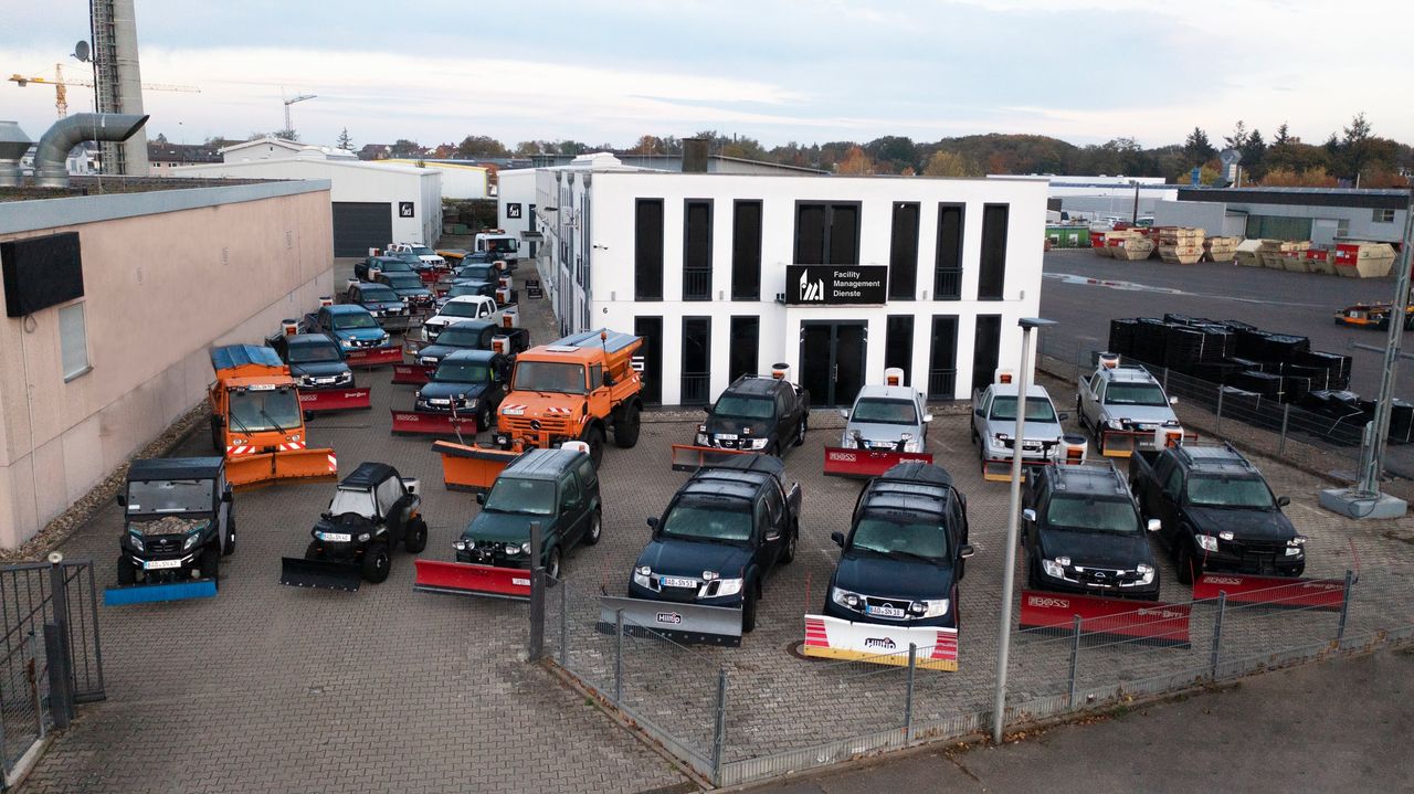 Firmengebäude der FMD mit Logo, davor der Fuhrpark für den Winterdienst: Geländewagen und Räumfahrzeuge mit Schneeschilden und Kehrbürsten