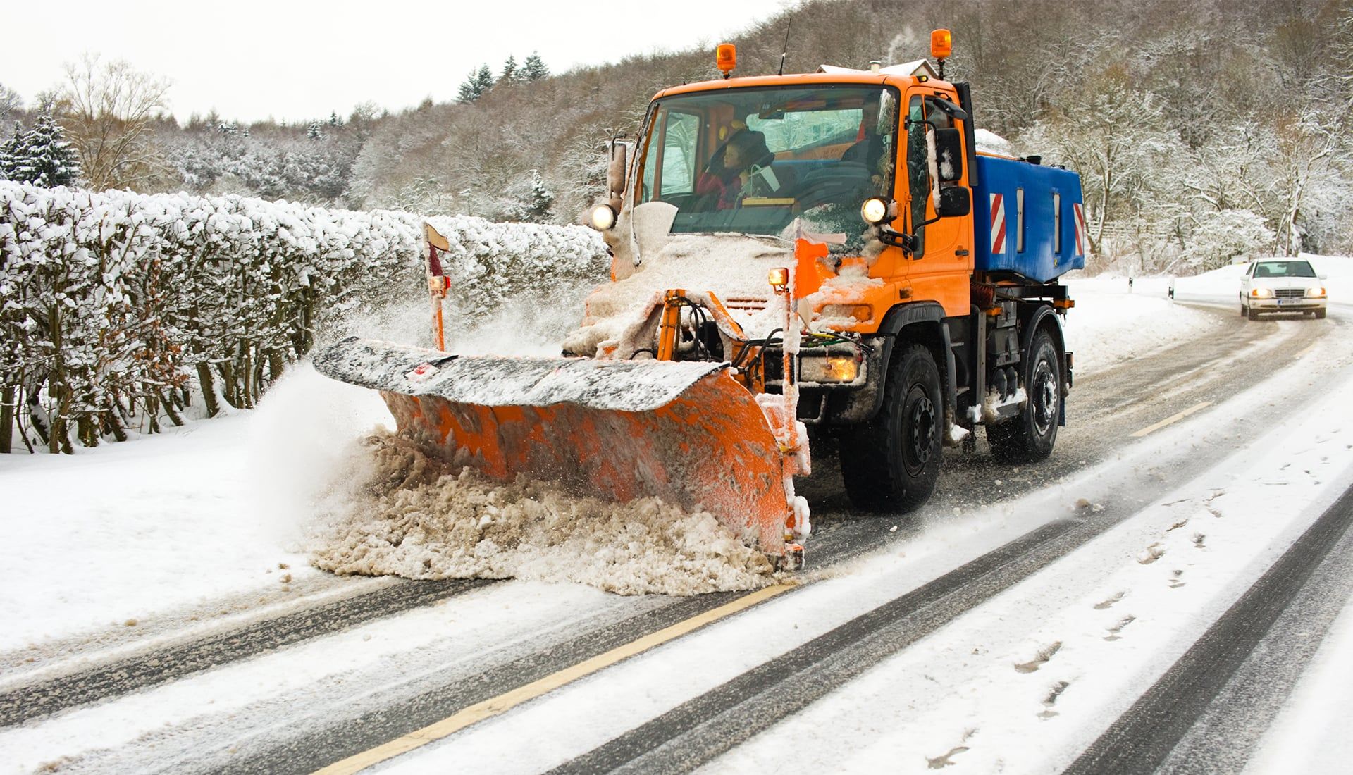 Räumfahrzeug mit Schneepflug auf einer verschneiten Landstraße