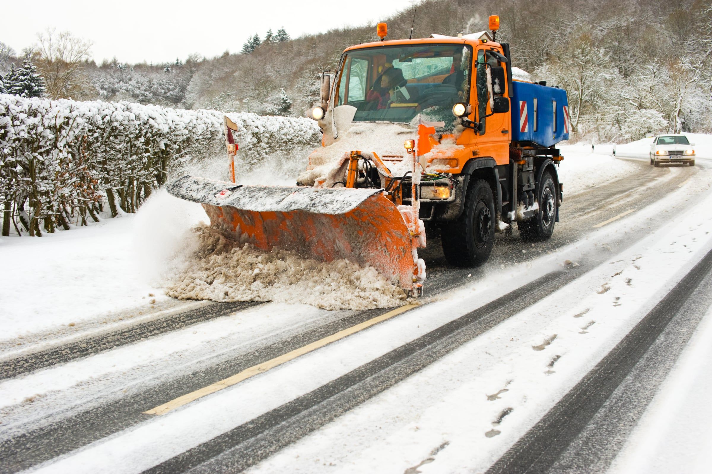 Räumfahrzeug mit Schneepflug auf einer verschneiten Straße